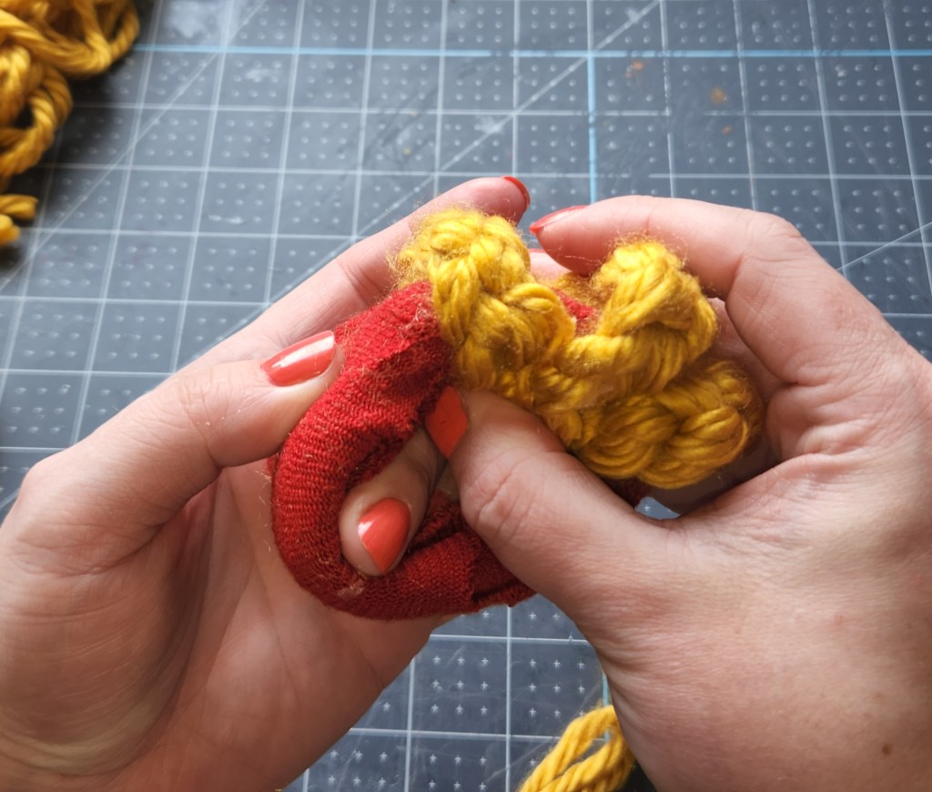 Gluing thick crocheted pieces of yarn on the bottom inside of the donut pumpkin.