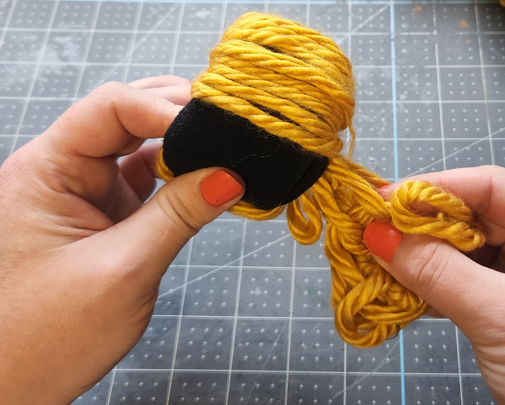 Passing yarn through the center of the sock bun, covering it.