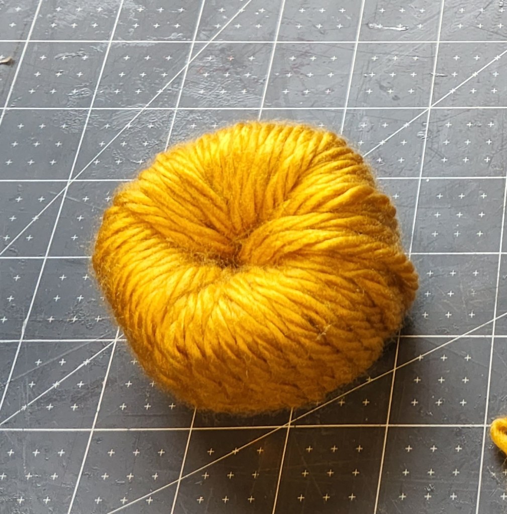Donut pumpkin covered in mustard yellow yarn.