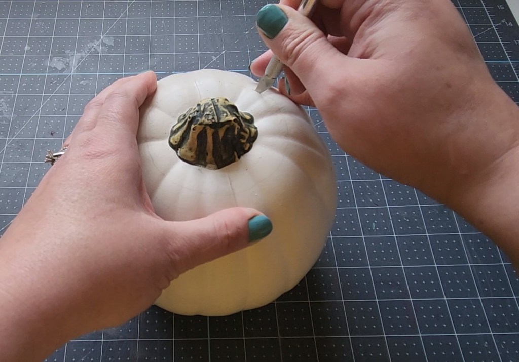Cutting the top off of the pumpkin with an exacto knife.