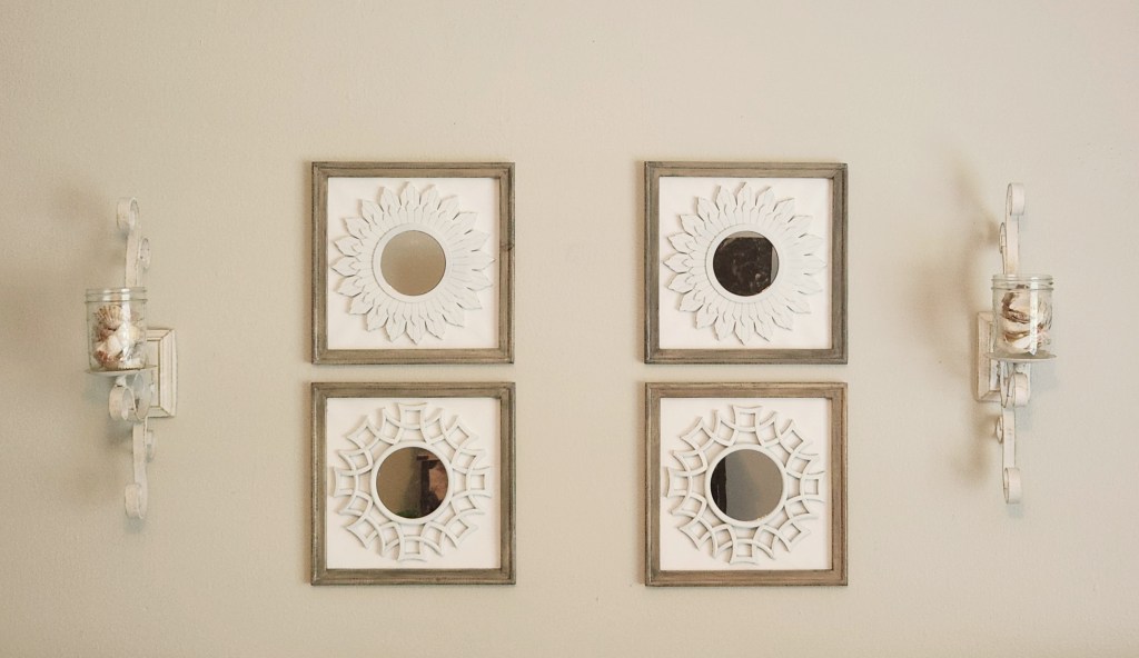 Duplicates of Pottery Barn mirrors; four framed mirrors, frames are weathered gray wood, mirrors are decorative shapes with circle mirrors. Candles sconces are hanging on each side of the set.