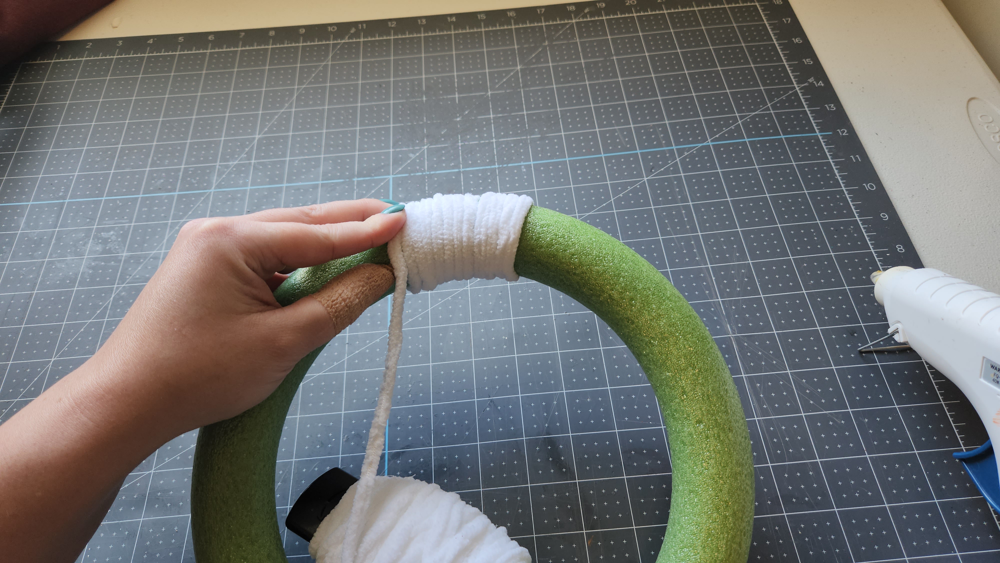 Wrapping the chenille yarn around the wreath form to cover it.