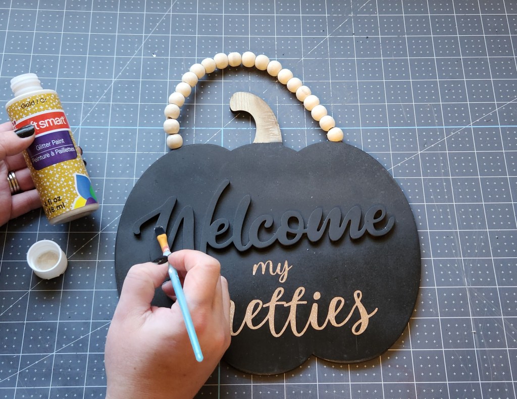 Painting over "welcome" with gold glitter paint.