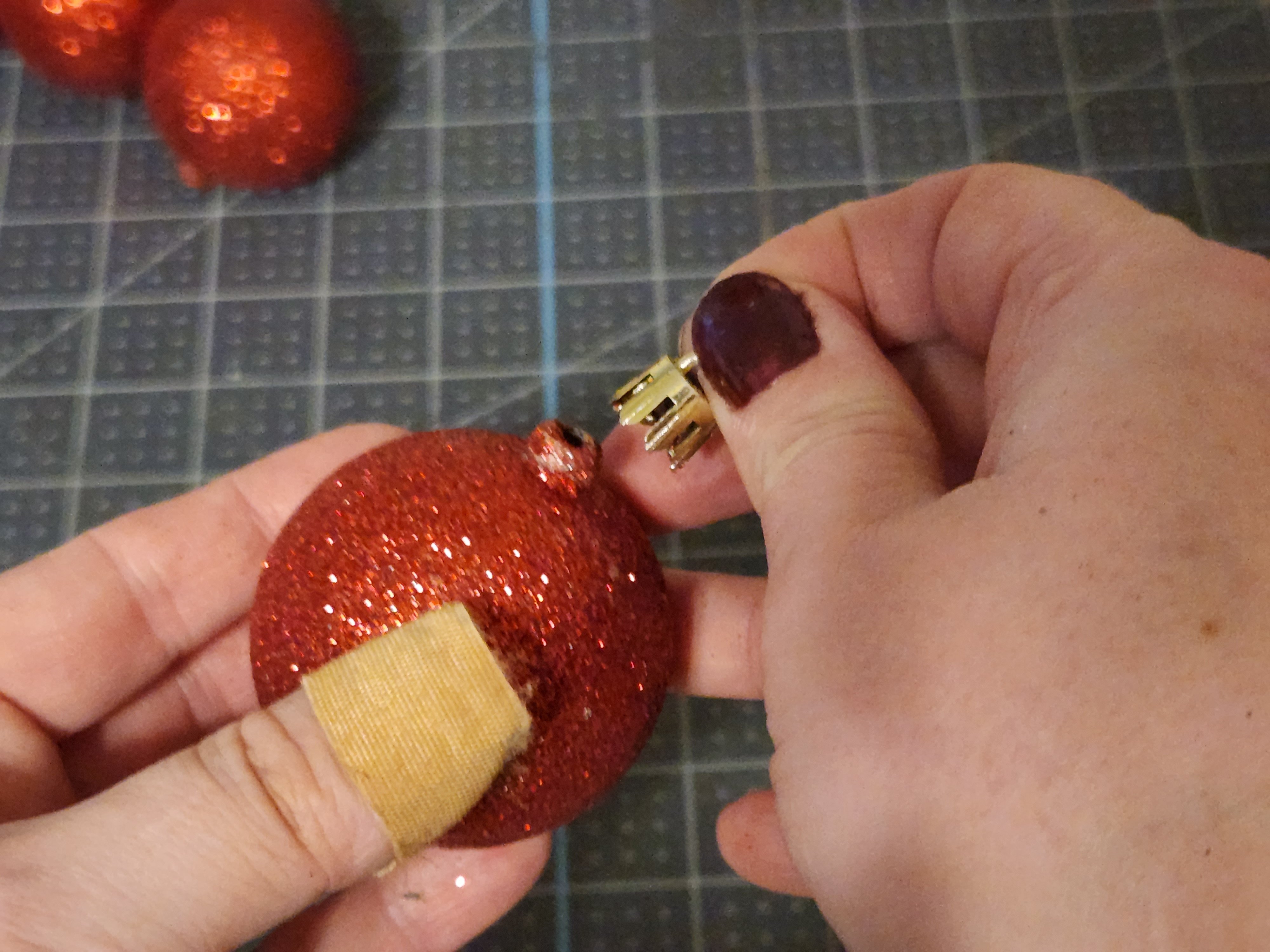 Pulling the gold hanger off of a ball ornament.