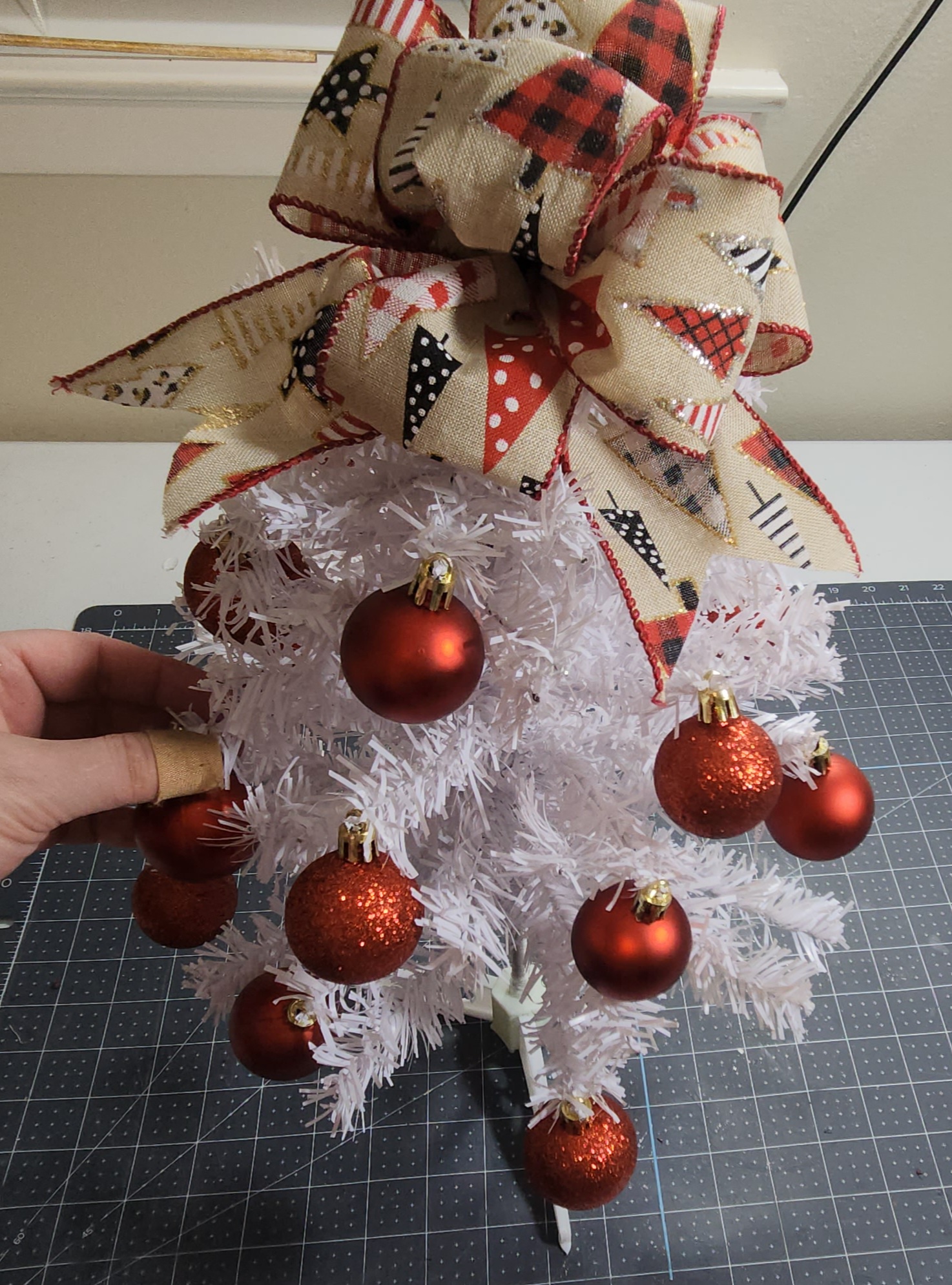 Sliding the hanger on the top of a ball ornament onto the tree branch.