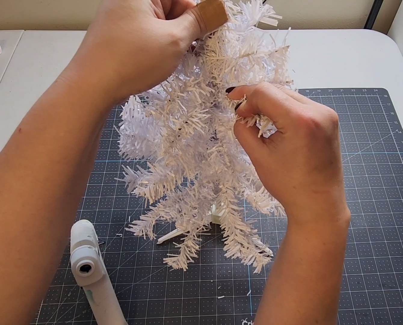 Holding a branch in place on the tree while the glue dries.