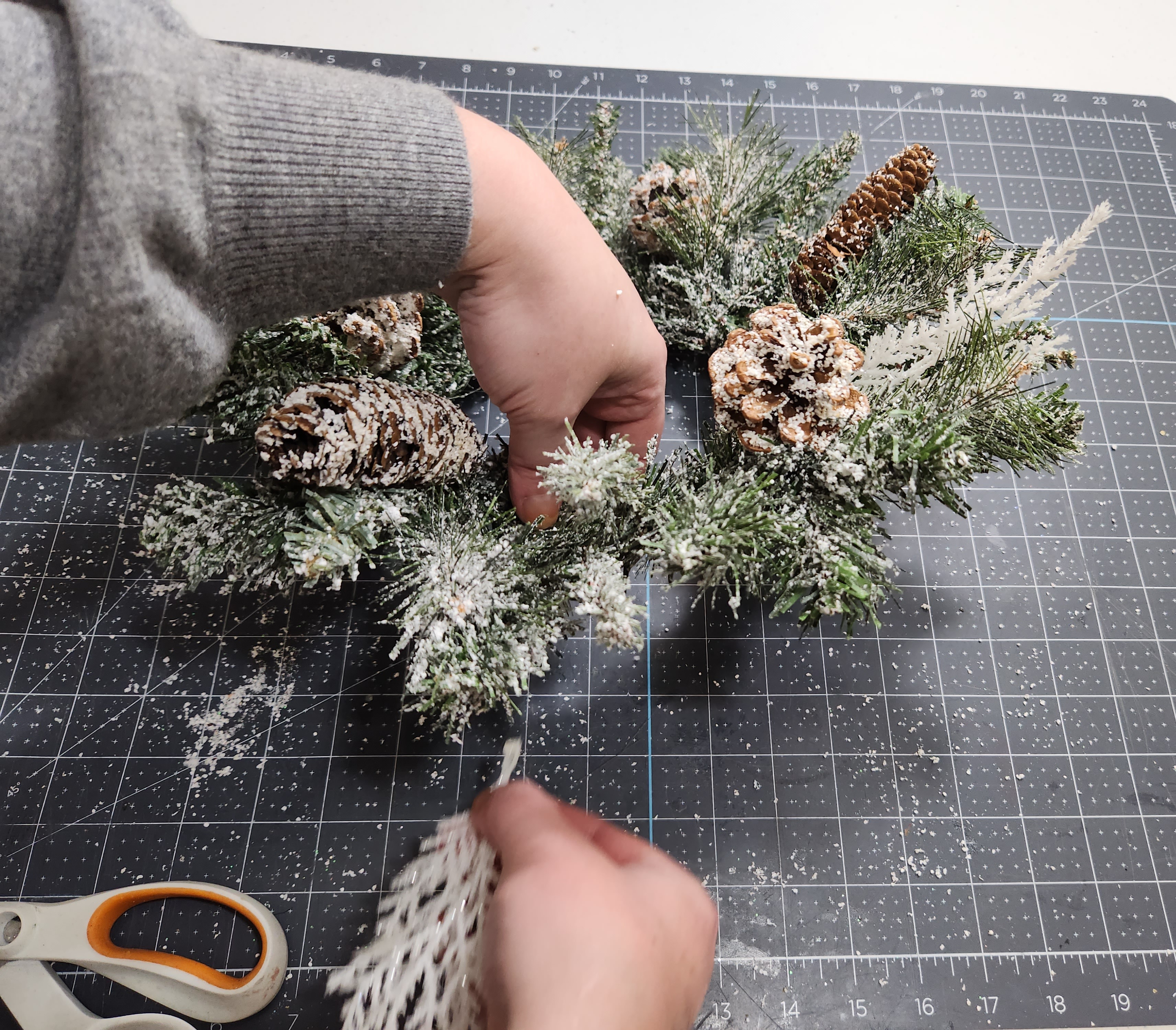 Gluing white glitter stems to the Christmas wreath.