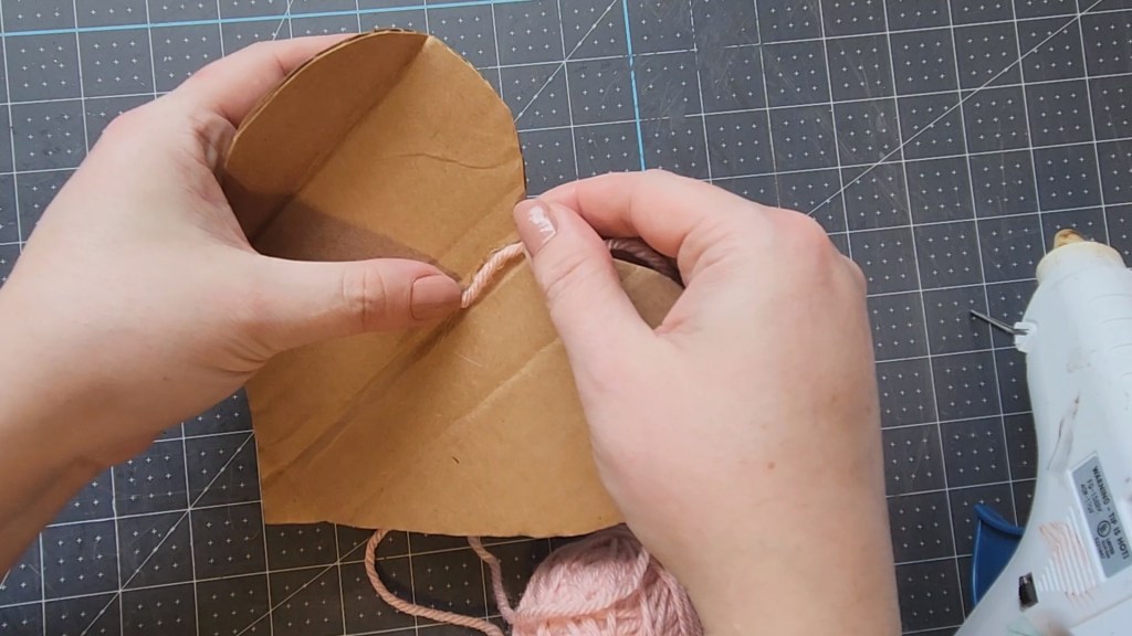 Placing yarn on the glue on a cardboard heart.
