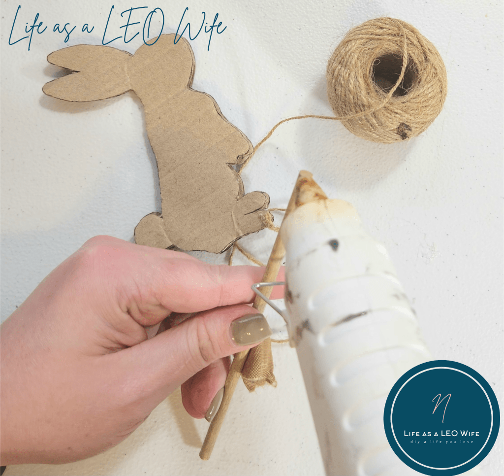 Putting hot glue on the end of a wood dowel to attach to the cardboard bunny.