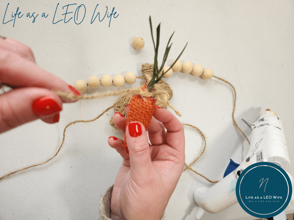 Moving a faux carrot further down the twine of the spring garland.