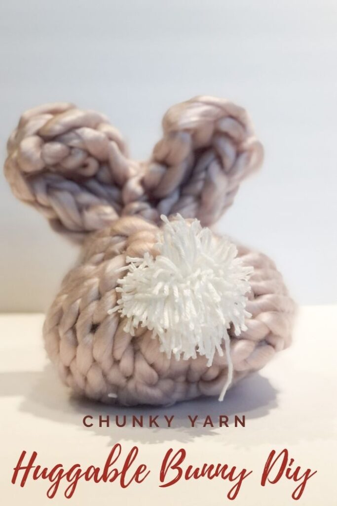 Dusty rose colored chunky yarn bunny with a white embroidery yarn pom pom tail.