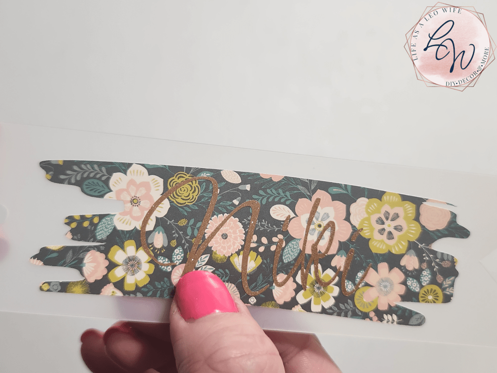 Dollar Tree bookmark with floral vinyl brush stroke shape and "Niki" in gold glitter vinyl on top.