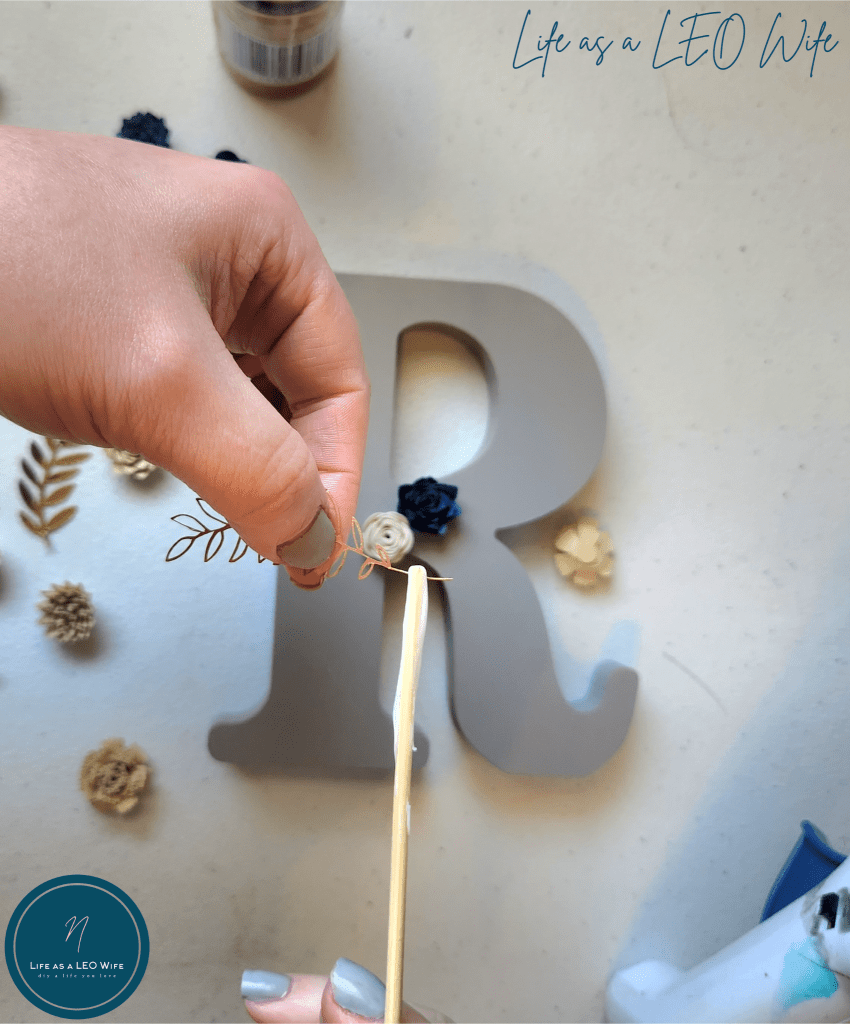 Putting glue on the back of a metallic gold leaf stem with a wood skewer.