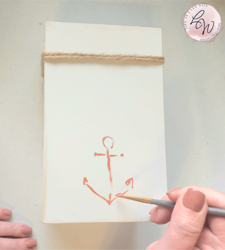 Upcycling a coastal farmhouse book set by painting a coral anchor on the top.