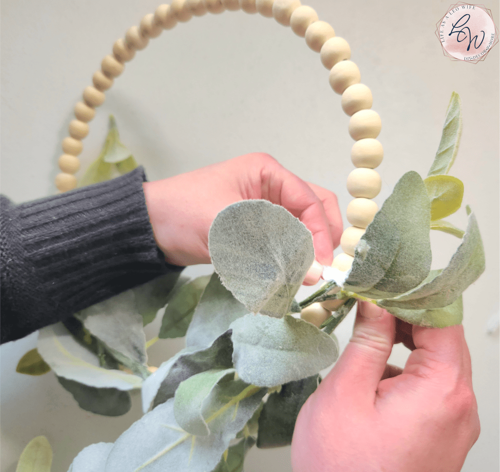 Attaching the left end of the lamb's ear garland to the bottom of the wood bead wreath.