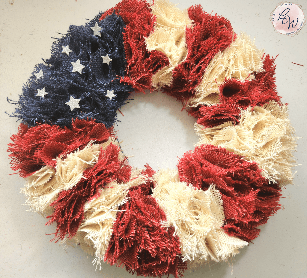 Finished patriotic burlap wreath with 7 red stripes. 6 white stripes, and a section of blue burlap with silver stars.