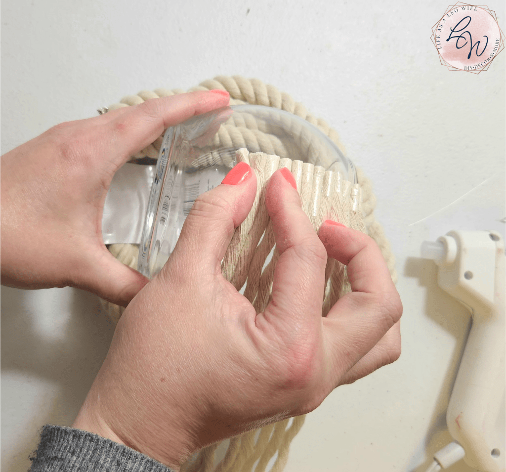 Pressing glued ropes on a round vase.