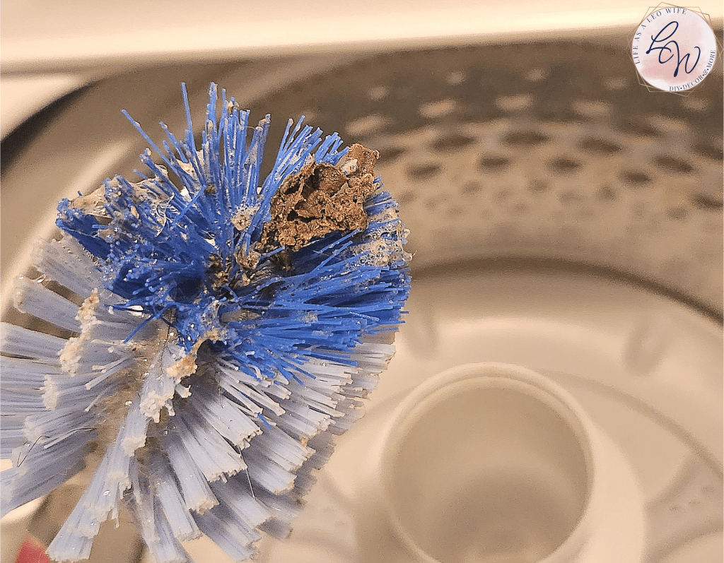 Scrub brush with dirt that has been scrubbed from the washing machine.