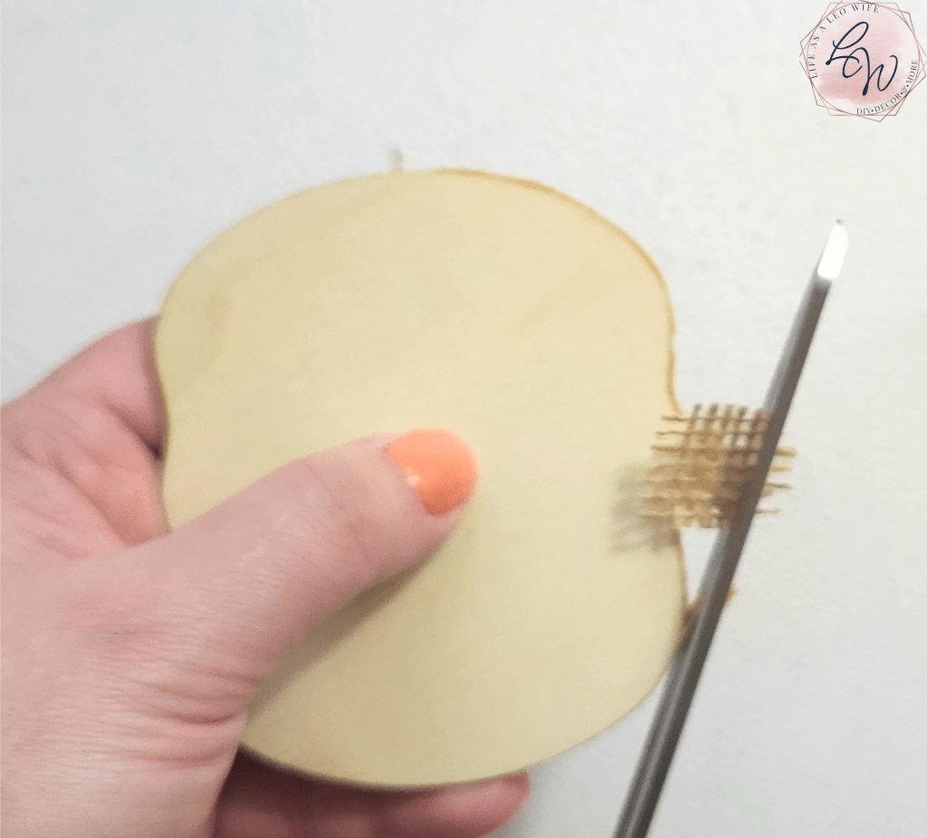 Cutting burlap attached to the stem of the pumpkin coasters.