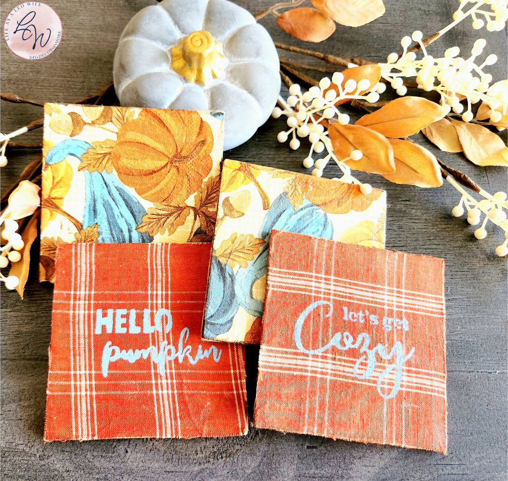 Fall coasters with a concrete pumpkin and fall stems behind them: 2 square coasters with pumpkins and gourds, 2 square coasters with rust and tan plaid base with "let's get cozy" on one and "hello pumpkin" on the other.