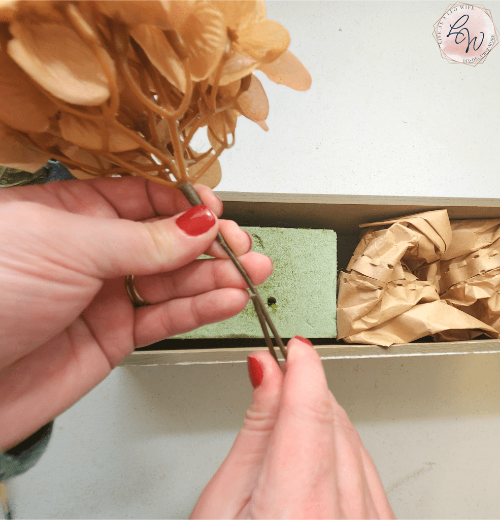 Bending the stem of a light copper hydrangea to place in the fall box.