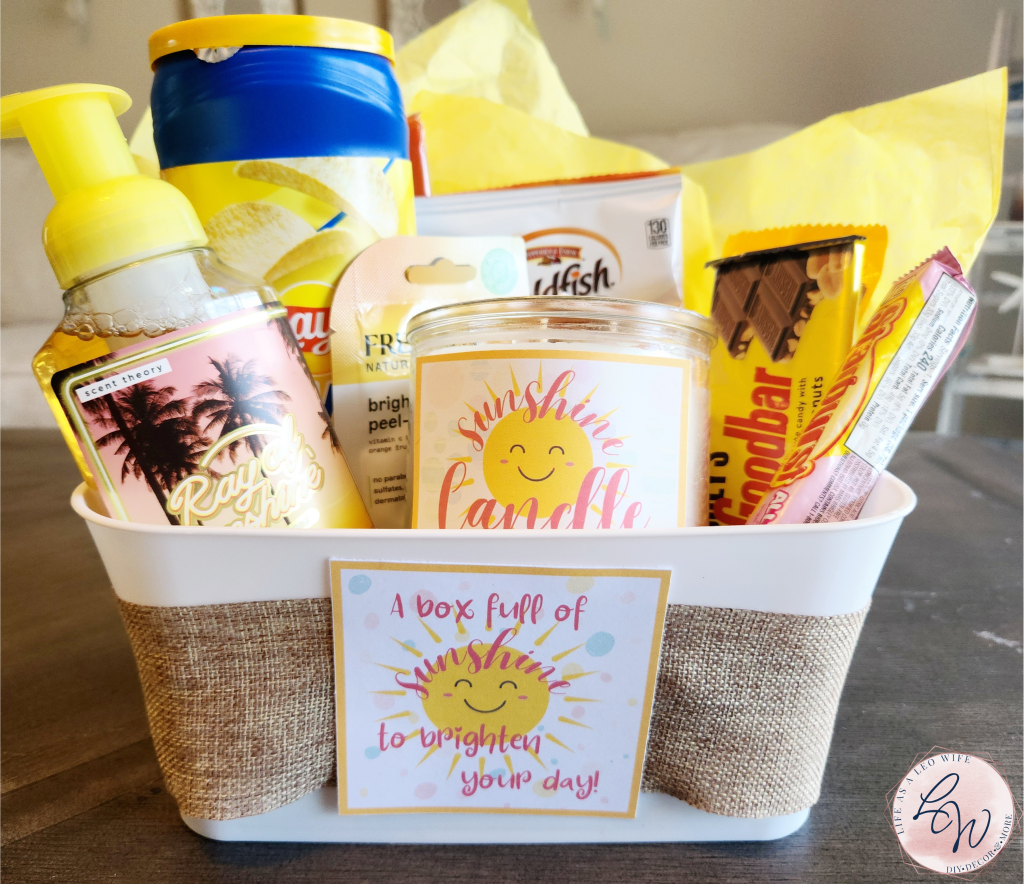 Complete sunshine box filled with yellow tissue paper, yellow hand soap with the label "Ray of Sunshine," Goldfish, Lay's chips, brightening face mask, Mr. Goodbar, Starburst, M&M's, peanut butter crackers, lip balm with a "shiny lip balm" label, and a 3-wick "sunshine candle."