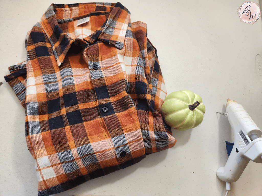 Supplies for a flannel shirt pumpkin: rust, blue, and white flannel shirt, styrofoam pumpkin, and hot glue gun and glue.