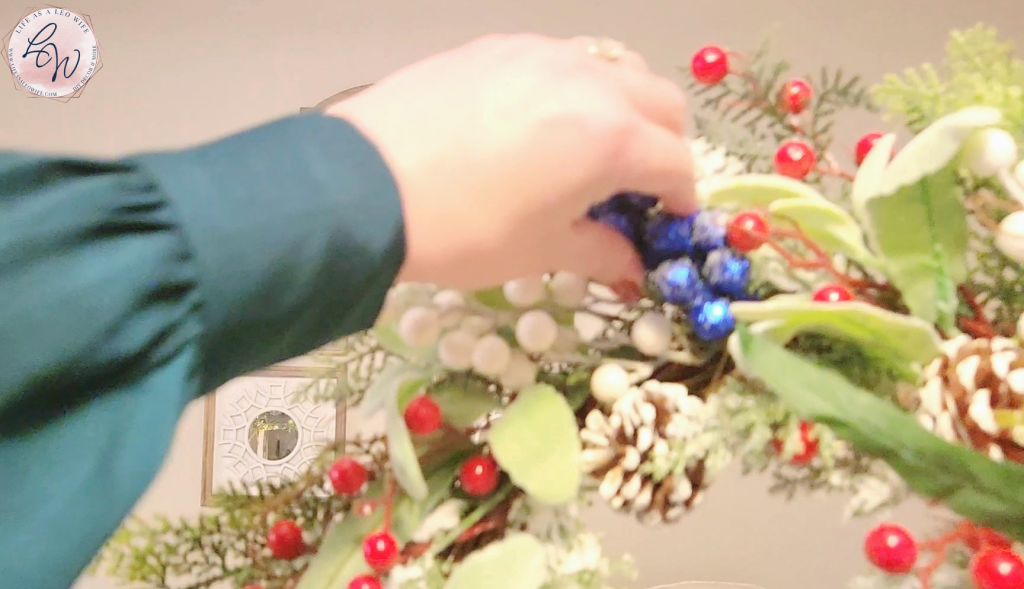 Putting a cobalt blue berry pick into a premade wreath.