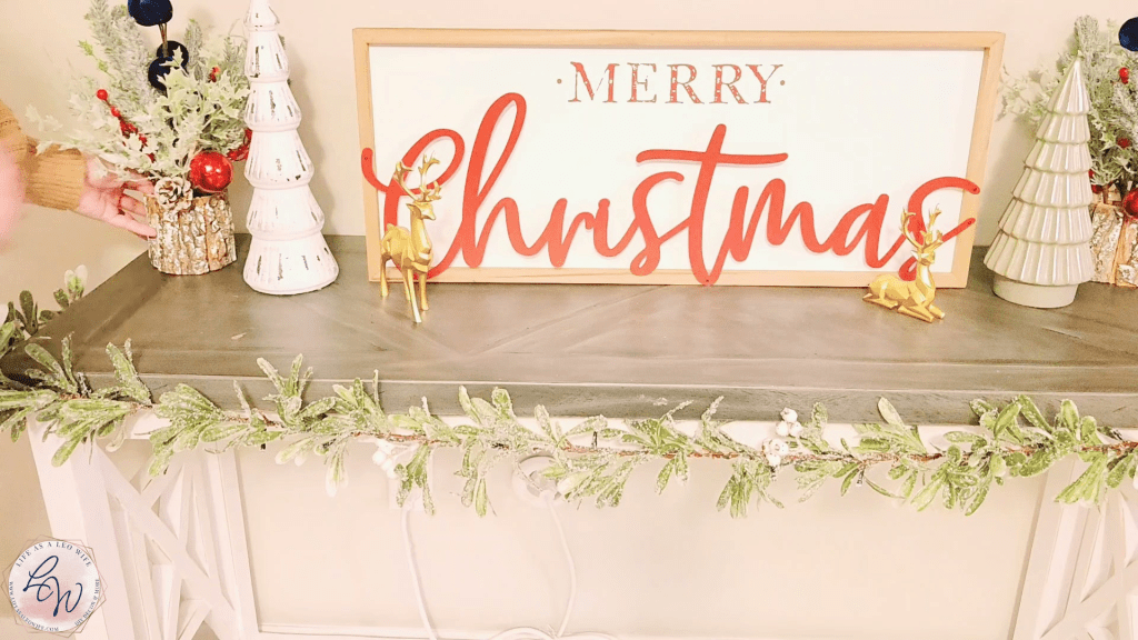 Placing a Christmas tree decoration in a tree trunk vase on left end of the Christmas mantle.
