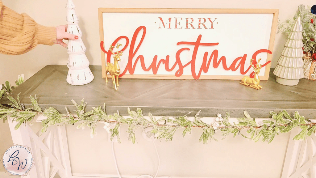 Placing a white glass Christmas tree from Hobby Lobby on the left side of the Merry Christmas sign in the center of the mantle.