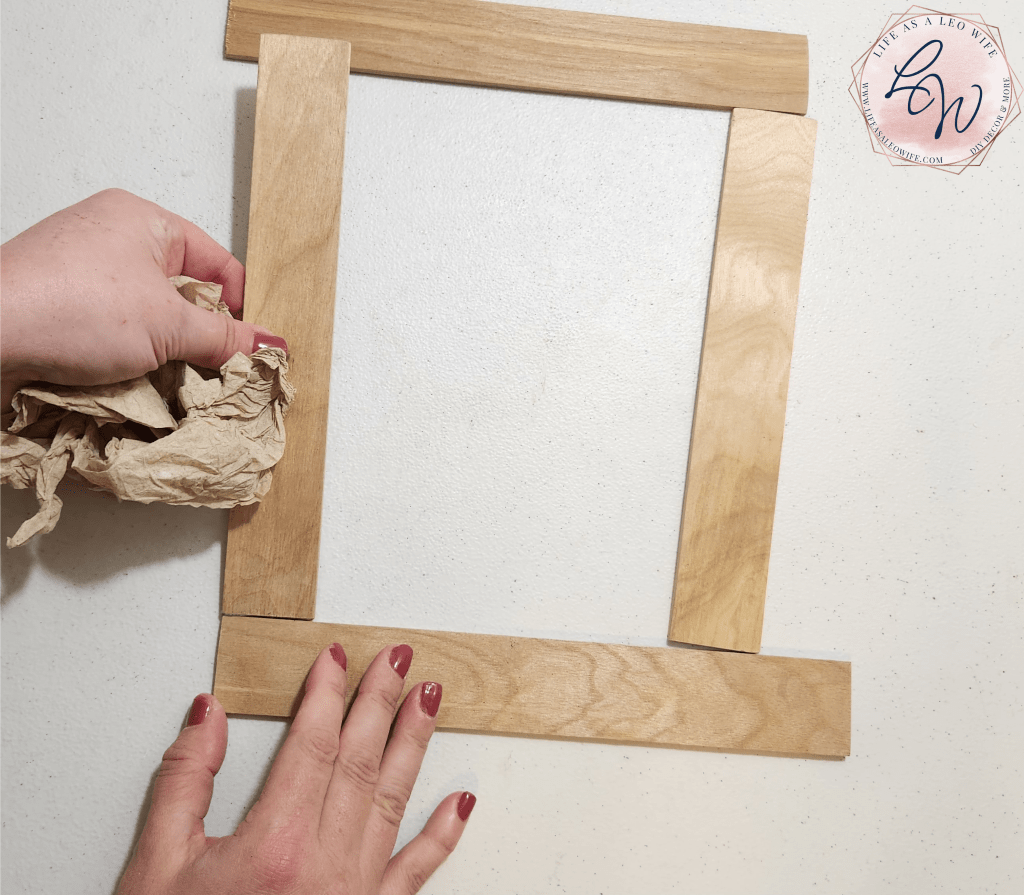 Placing the glued pieces of wood together to make a wall art frame.