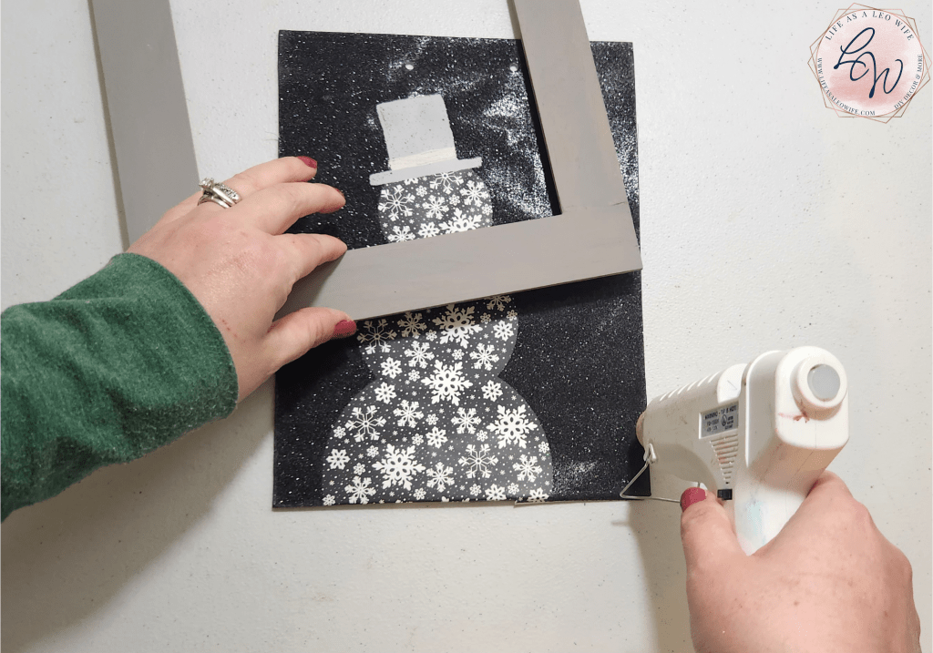 Putting hot glue on the edge of the small gift bag to glue the frame on it.