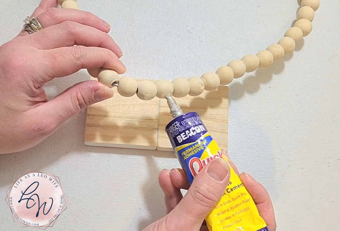 Adding Quick Grip to the bottom 3 beads of the wood bead heart to place it on the base of the Valentine's Day decoration.