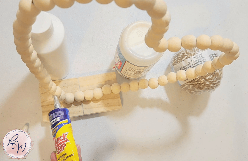 Adding Quick Grip to the bottom 3 beads of the wood bead heart to attach the wood heart to it.