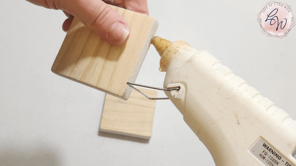 Adding hot glue to a wood block after Quick Grip to create the base of the Valentine's shelf sitter.