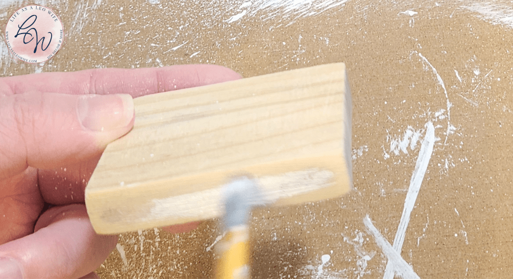 Painting the edge of the wood block white.