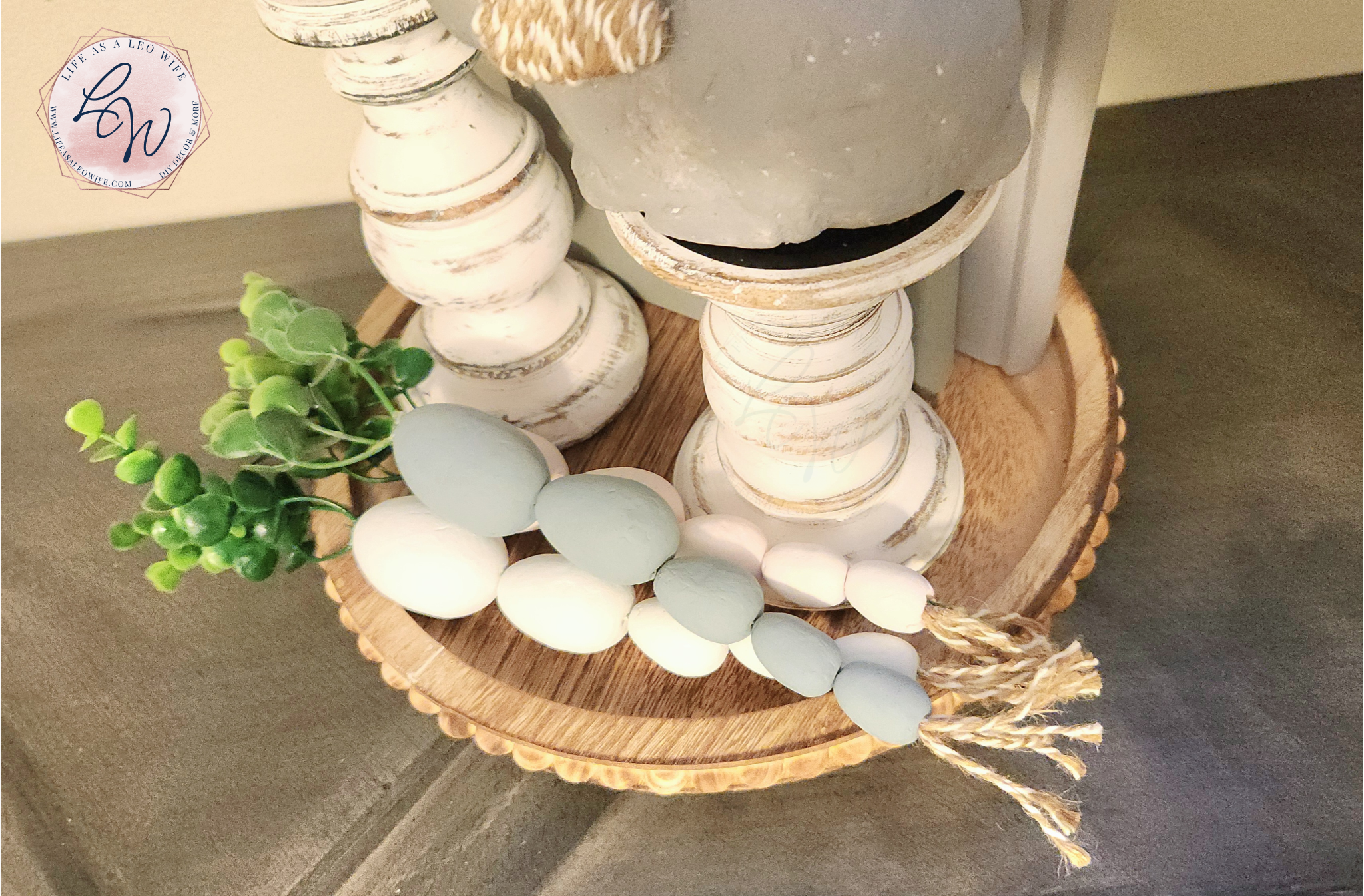 Easter egg carrots laying on a farmhouse wood tray with 2 candlestick holders, a bunny, & 2 decorative books (view from above).