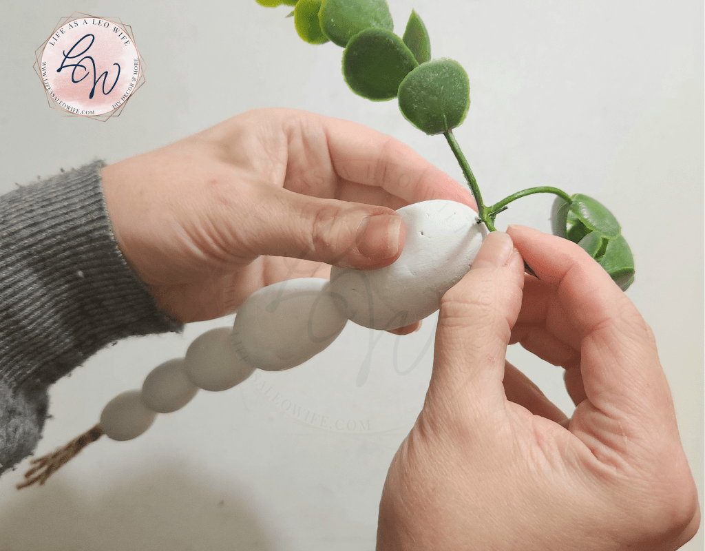 Sliding the eucalyptus branch down onto hot glue on the top of the Easter egg carrot.