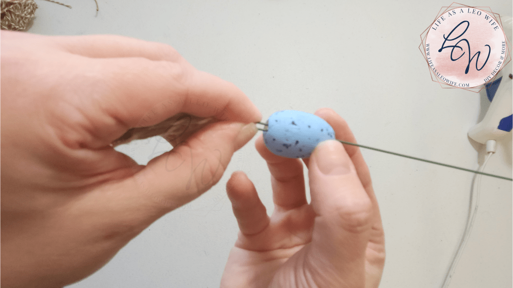Pushing the 1st egg down over the bent wire with the twine.