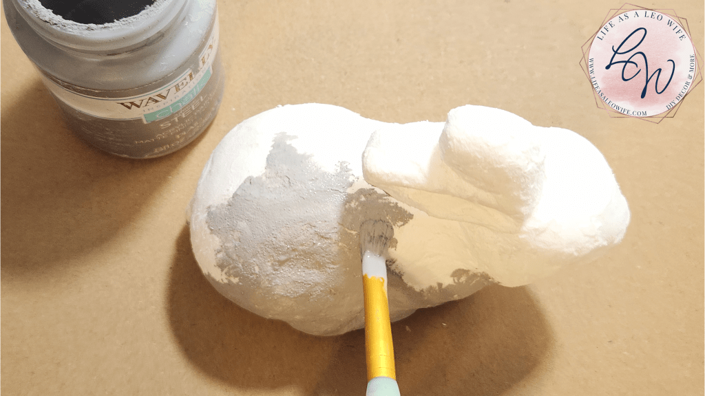Dabbing gray chalk paint to look like faux concrete on the dried spackling on the styrofoam bunny.