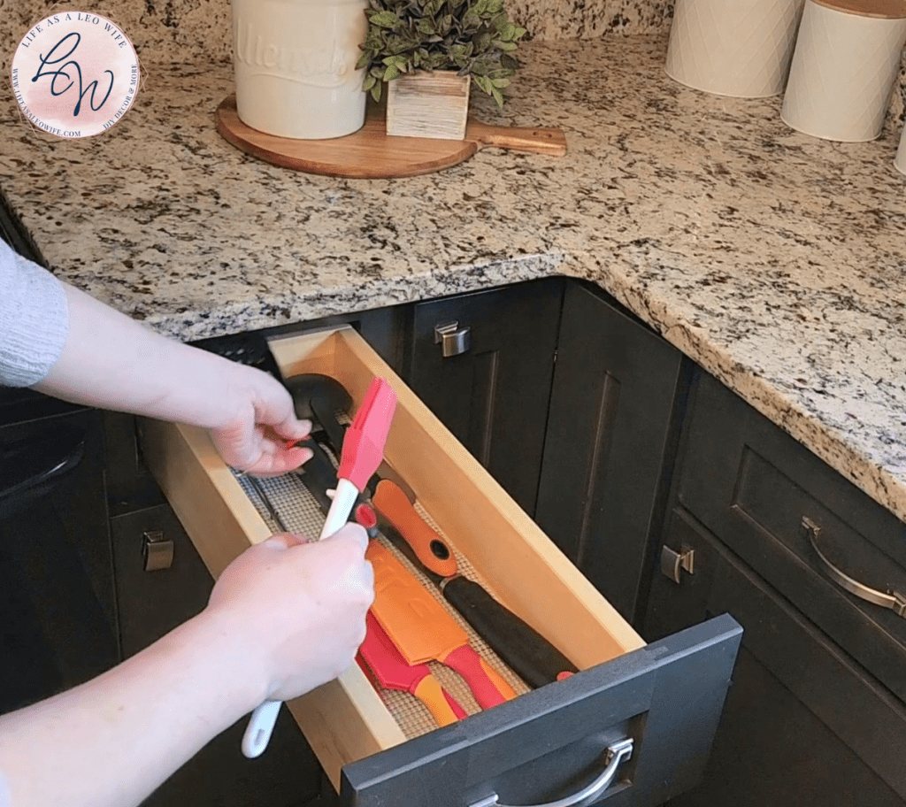Placing cooking utensils back in the organized drawer.