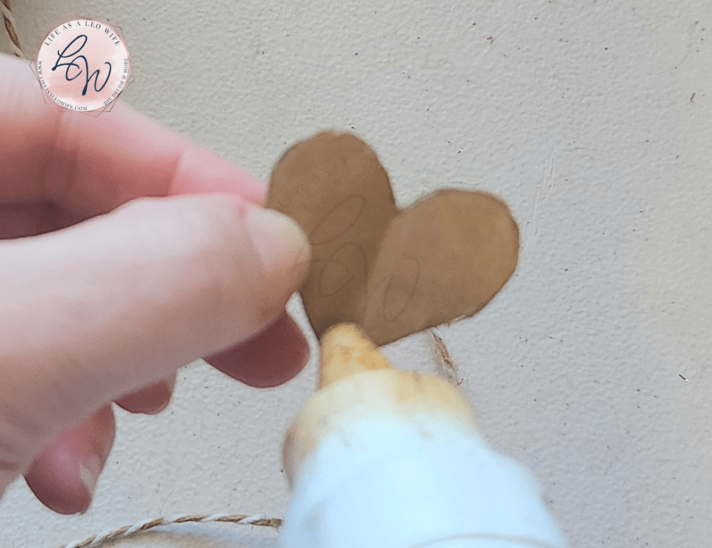 Putting hot glue at the bottom of the cardboard heart to attach twine to it for the faux concrete bunny.