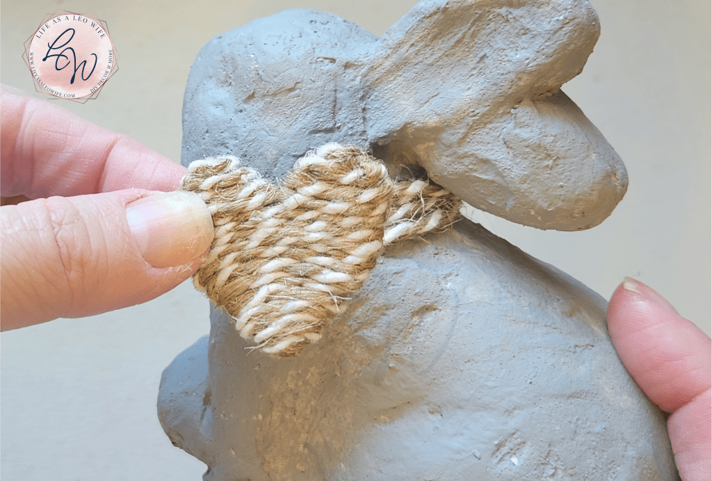 Gluing heart to the twine around the neck of the DIY faux concrete bunny.