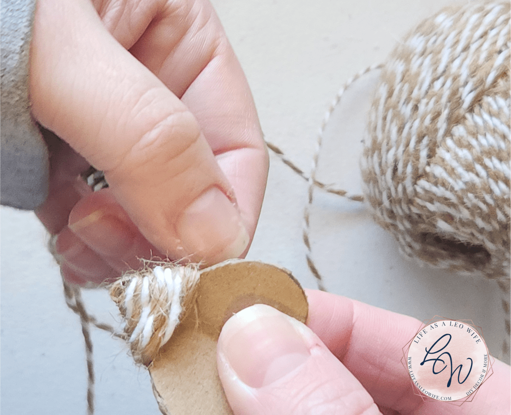 Wrapping twine about 1/4 of the way up the cardboard heart that will be glued to the DIY faux concrete bunny.