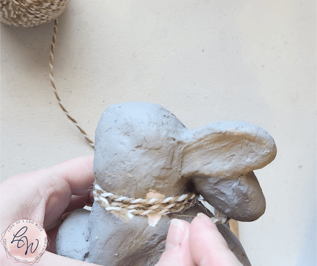 Wrapping twine around the neck of the DIY faux concrete bunny.