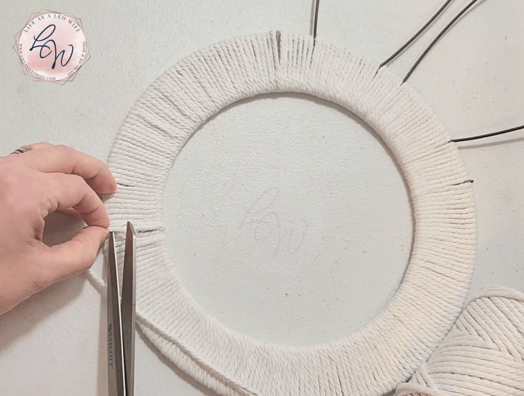 Cutting the extra cord off after covering the bunny wreath with it.