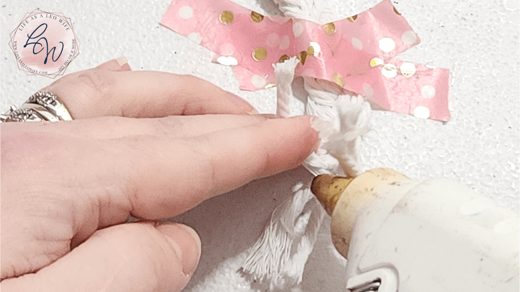 Putting hot glue on the end of the macrame cord braid to hold it together.