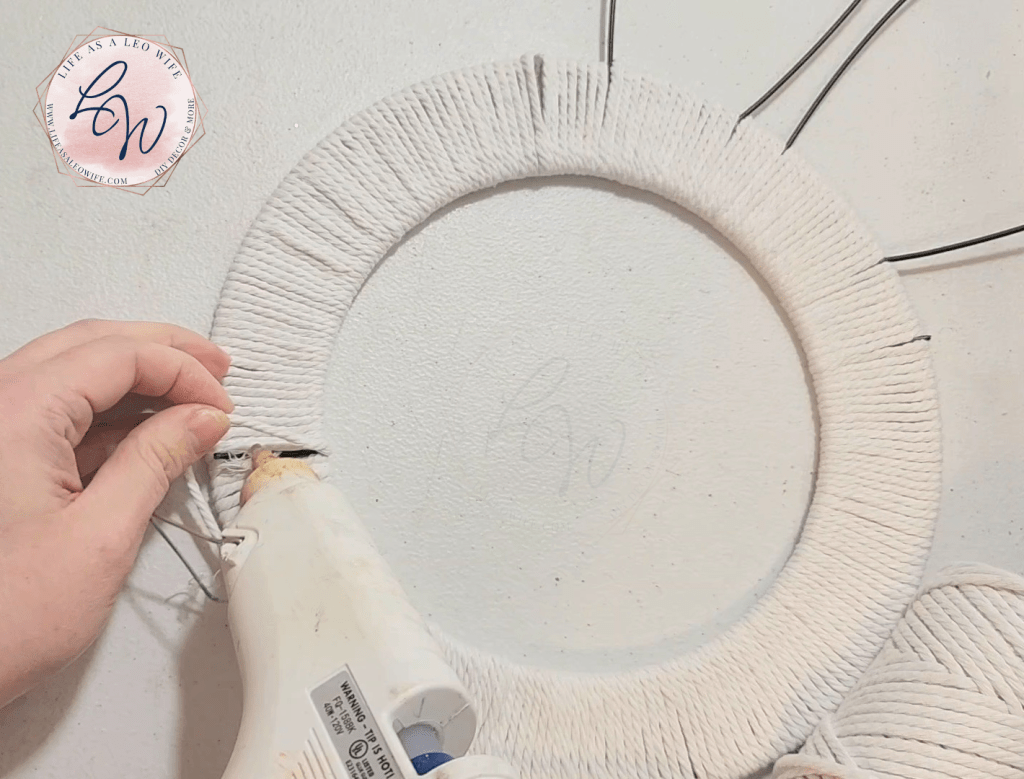 Gluing the macrame cord to the back of the round section of the wreath after it's completely covered.