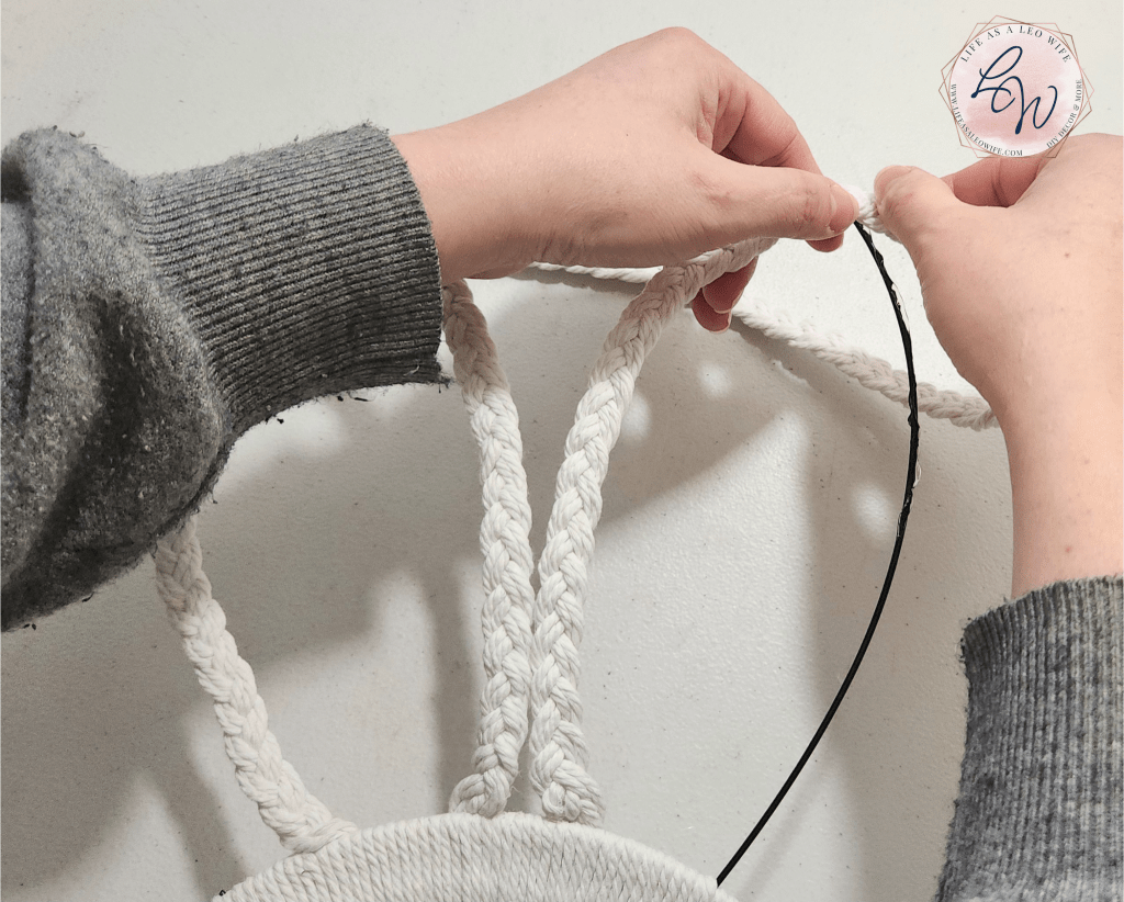 Pressing the braided cord to the tip of the wire ear on the bunny wreath form.