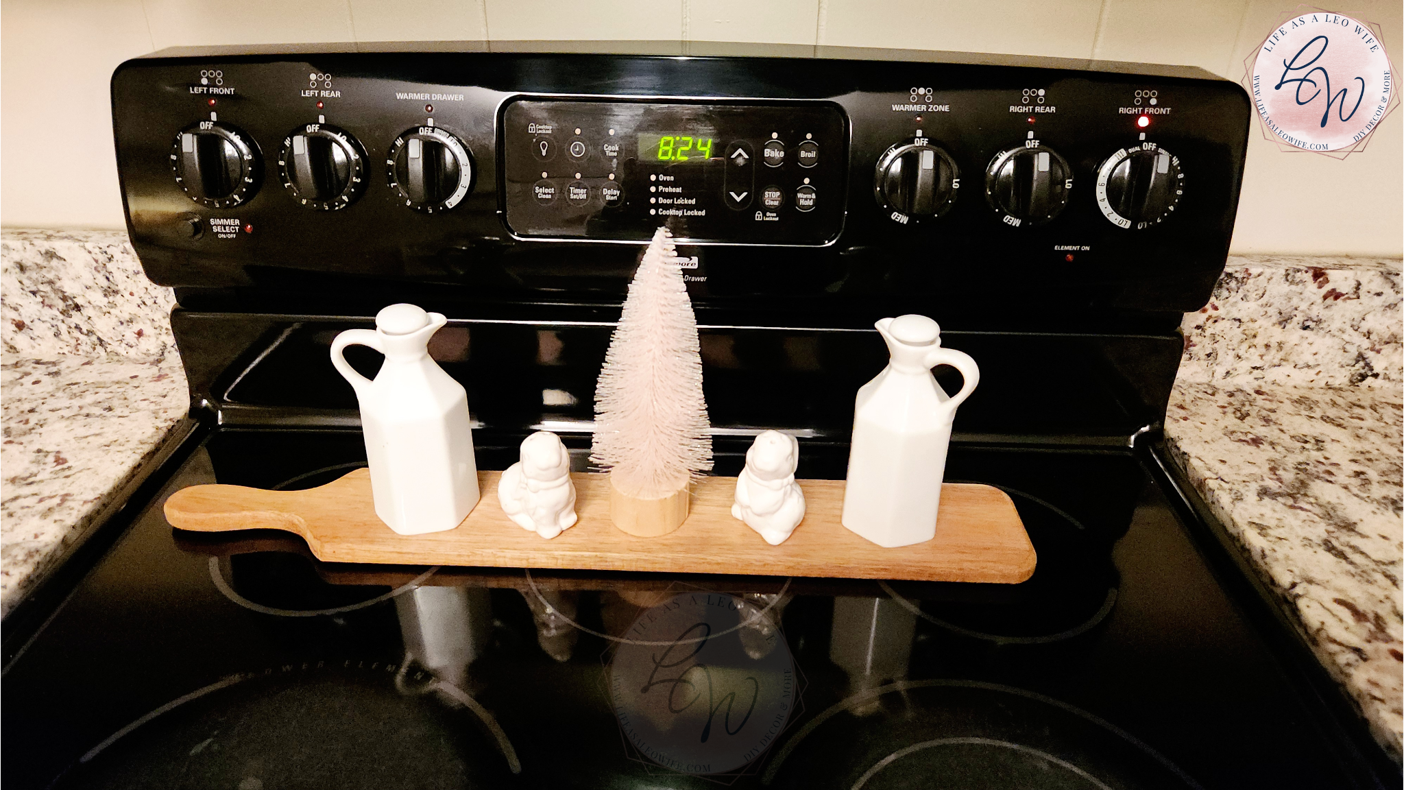 Easter / spring decor on a long, thin acacia wood tray on the stove with oil cruets, bunny salt & pepper shakers, & a light-up bottle brush tree.